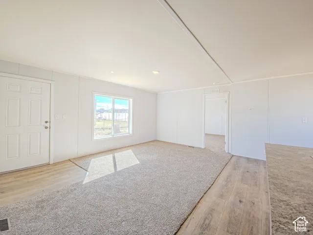 Hardwood-finish flooring, neutral carpeting, white interior doors, and a window with natural light