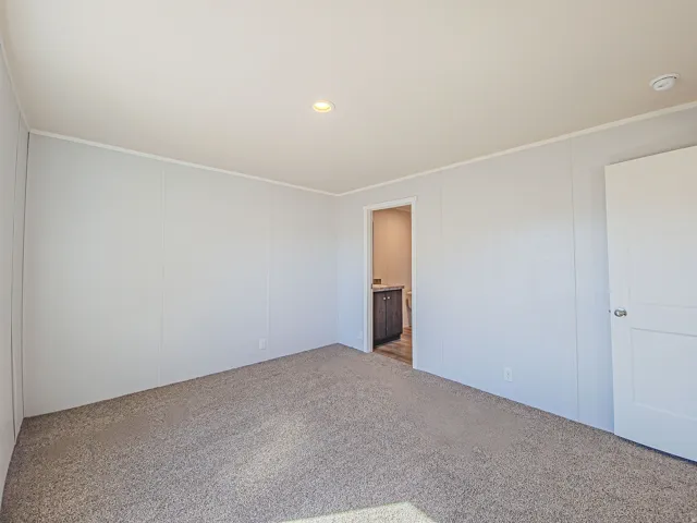 Carpeted room with recessed lighting and a white paneled door