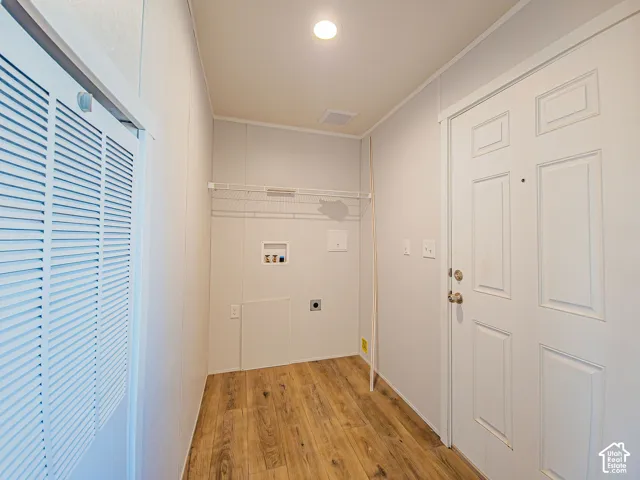Dedicated laundry area with hookups, wood-finish flooring, and a wire shelving unit