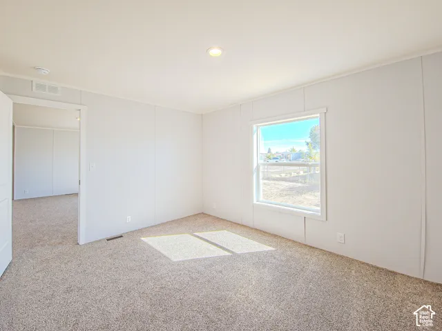Neutral wall finishes, recessed ceiling lighting, and plush carpet flooring