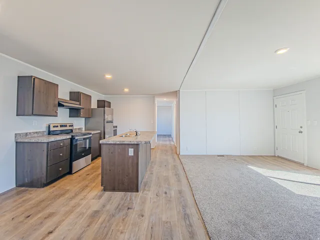 Kitchen island with sink, stainless steel appliances, wood-finish flooring, recessed lighting, and dark wood-finish cabinetry