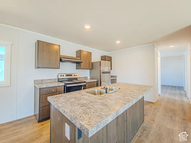 Kitchen featuring wood-finish cabinetry, stainless steel appliances, a center island with an integrated sink, and wood-finish flooring