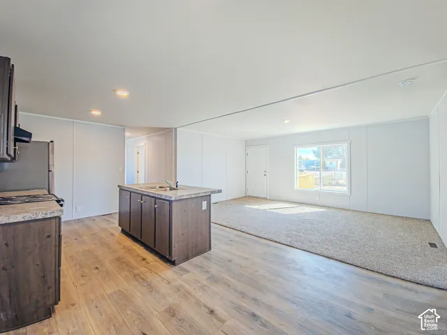 Wood-finish flooring, central kitchen island with integrated sink, recessed lighting, and a large window