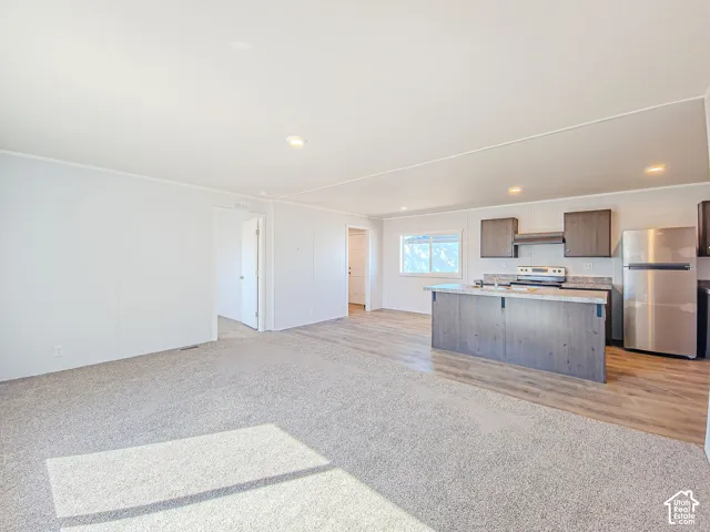 Open-concept living area with light gray carpeting and wood-finish flooring