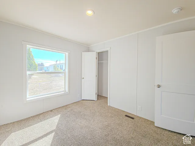 Recessed ceiling lighting, white panel doors, neutral carpeting, and a window with white trim