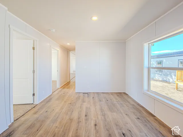 Recessed lighting illuminating wood-finish flooring, white paneled walls, and a large window