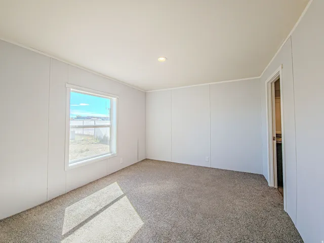 Recessed ceiling lighting, carpeted flooring, and a single window with white trim