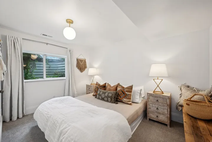 Carpeted bedroom featuring a white ceiling, a white wall, and a window with white trim
