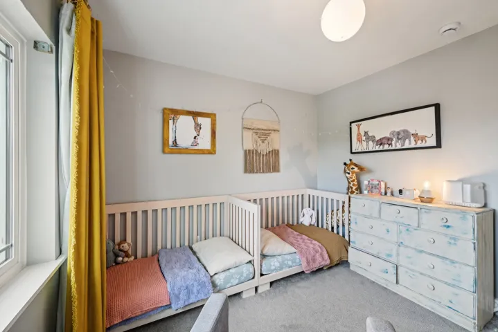 Light-filled room featuring two built-in cribs, a window with white framing, and a ceiling-mounted light fixture