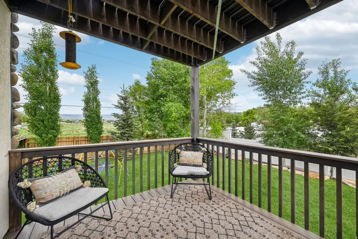 Covered deck with wood-finish flooring and dark wood railings