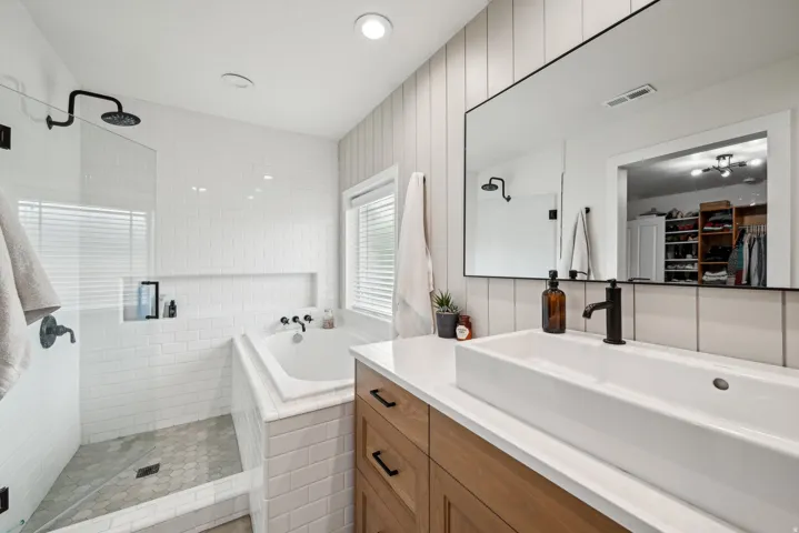 Modern bathroom featuring a walk-in shower with a glass enclosure and hexagonal tile flooring, a built-in bathtub, a vanity with wood-finish cabinetry, a rectangular vessel sink, and a large wall-mounted mirror