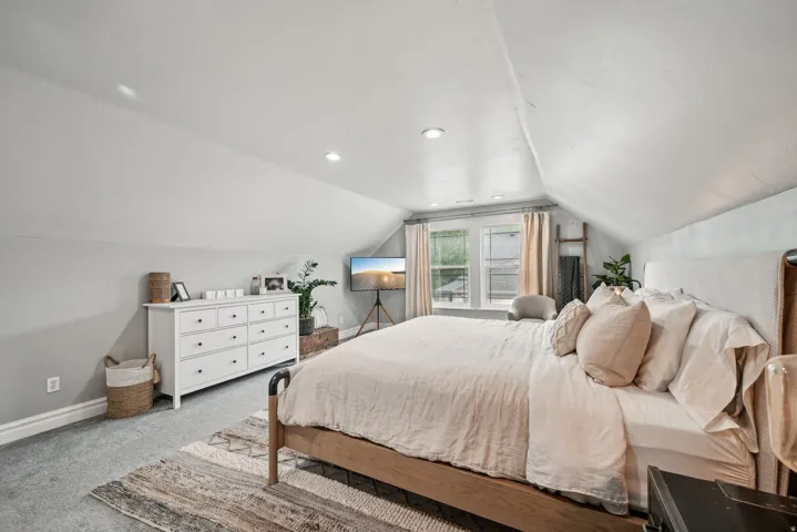 Bedroom featuring vaulted ceilings, recessed lighting, double windows, gray carpeting, and white baseboards
