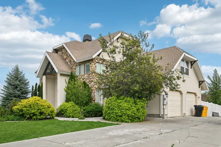 Two-story residence featuring a stone and stucco exterior, gabled rooflines, and a covered entryway