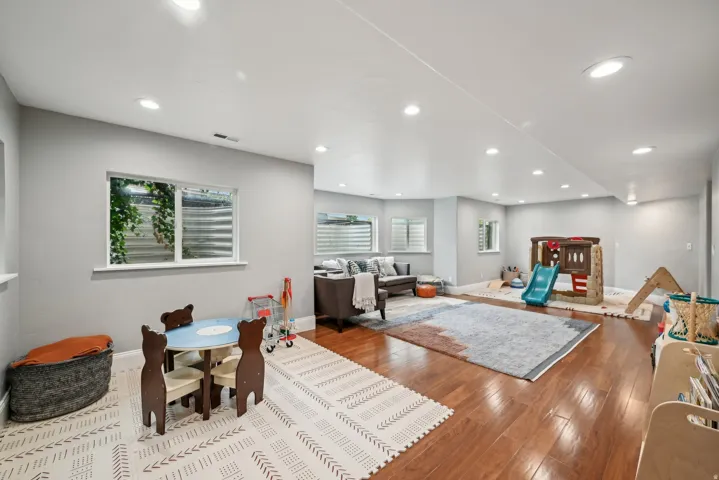 Spacious lower-level room featuring recessed lighting, light gray walls, and wood-finish flooring