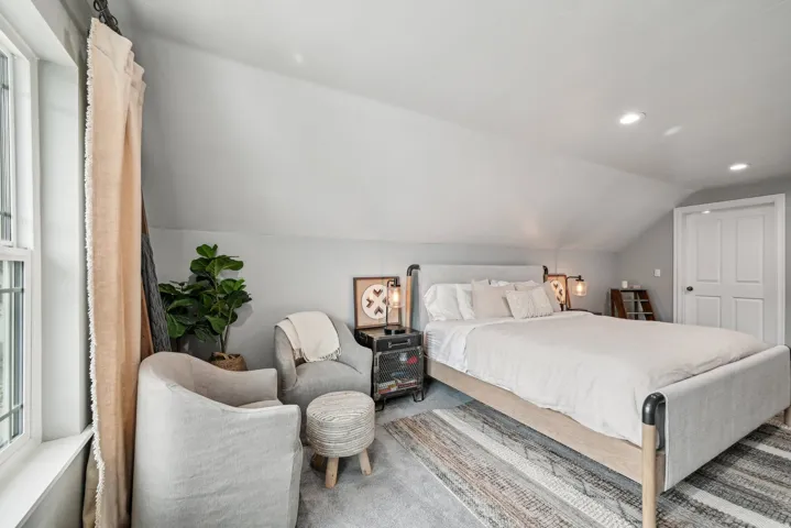 Attic bedroom with an angled ceiling, recessed lighting, and a paneled door