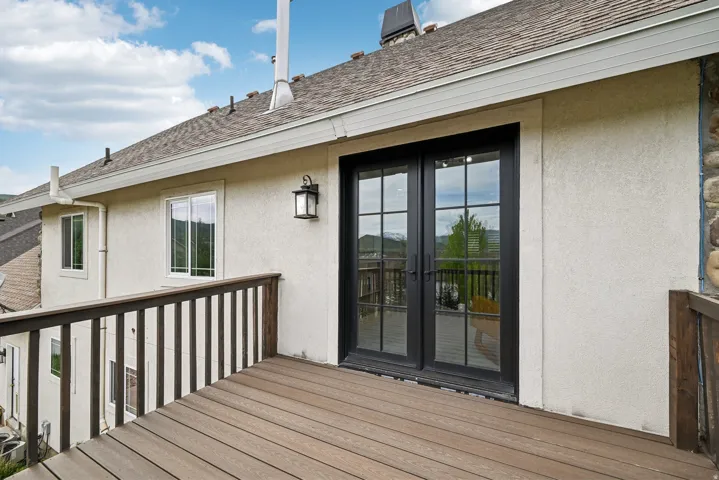 Outdoor deck featuring composite decking, dark wood railings, and a stucco exterior
