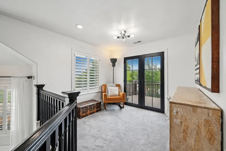 Upper-level landing featuring black framed French doors opening to a balcony