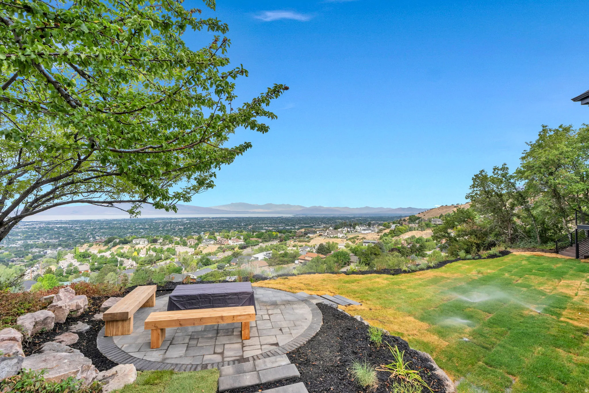 Expansive outdoor patio featuring a paved circular fire pit area with built-in wooden benches