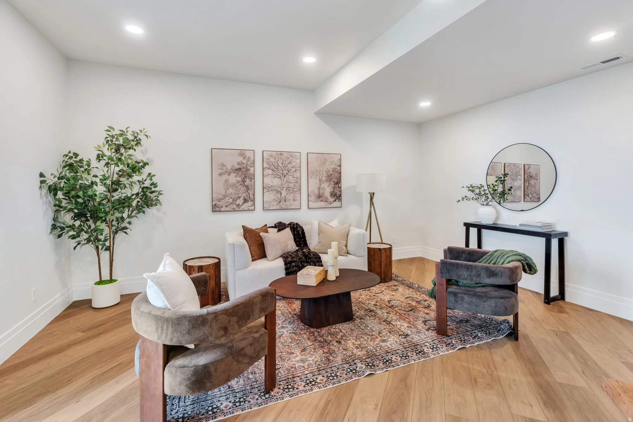 Spacious living area featuring light wood-finish flooring, recessed lighting, white baseboards, and crisp white walls