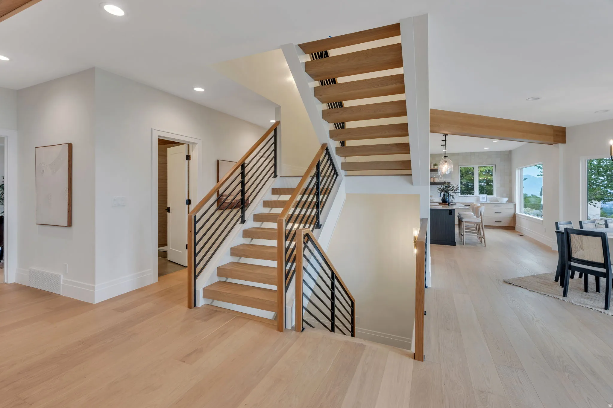 Open-riser staircase featuring wood-finish treads and contemporary metal railings