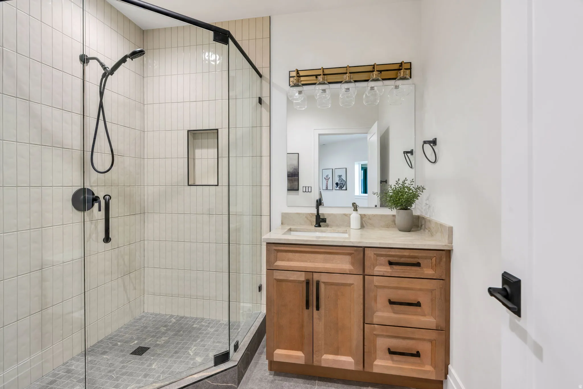 Shower enclosure with clear glass panels, matte black fixtures, and vertical stacked tile surround