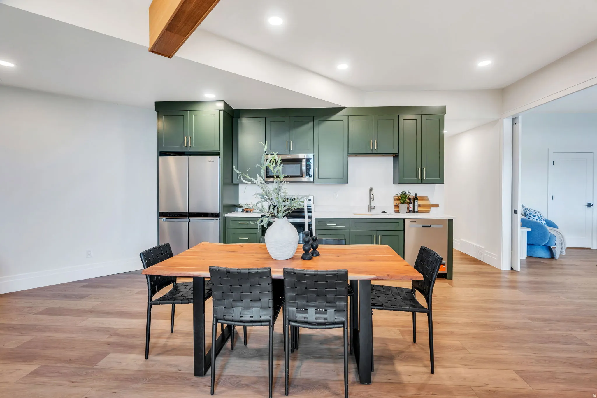 Contemporary kitchen featuring dark green cabinetry, stainless steel appliances, and a light-toned countertop