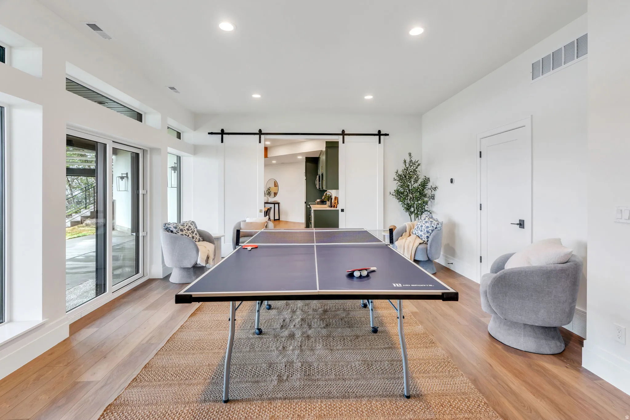 Spacious room with wood-finish flooring, a contemporary area rug, and recessed lighting