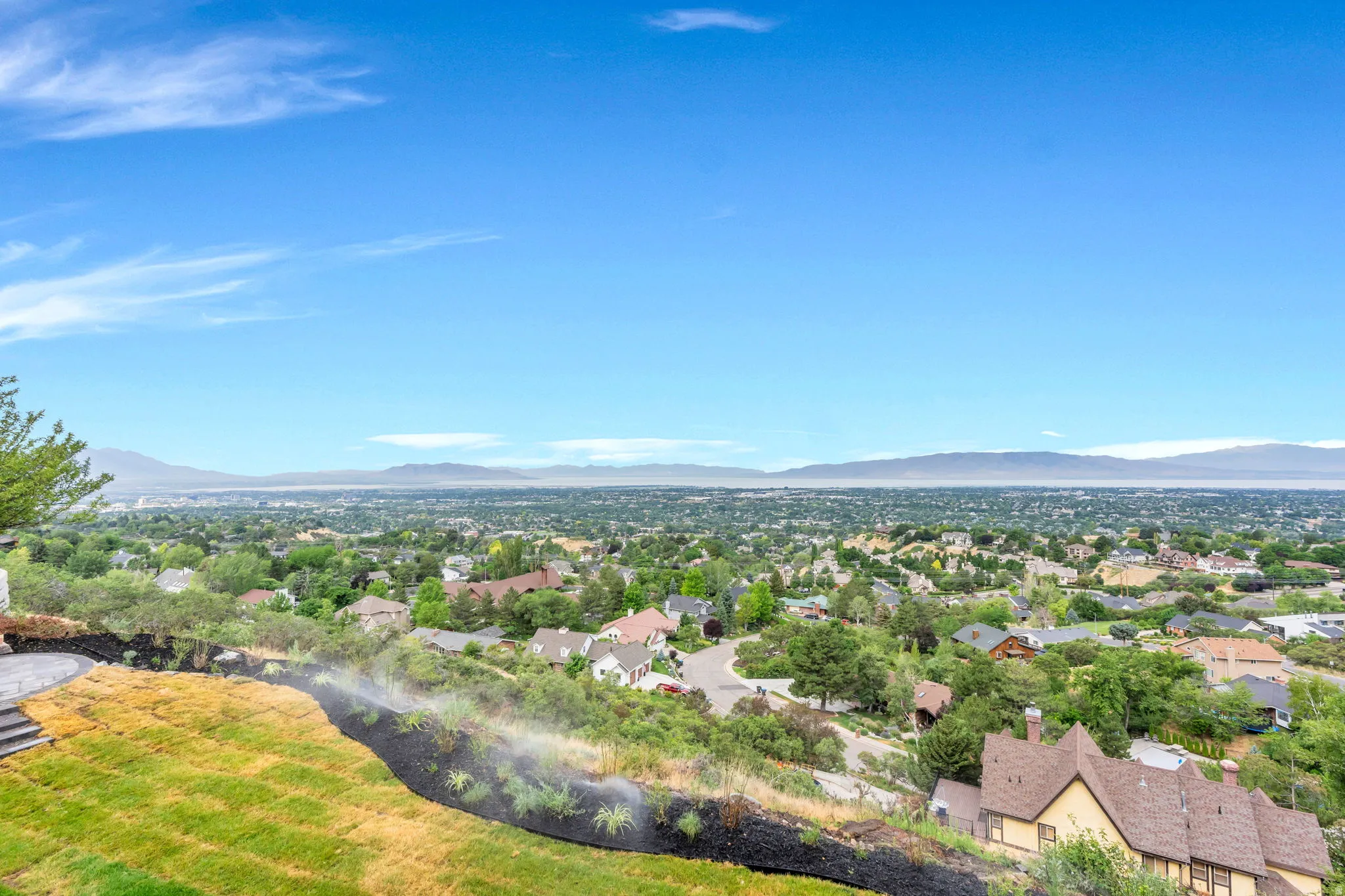 Expansive hillside property featuring a multi-level terraced lawn, a paved patio, and a sprinkler system
