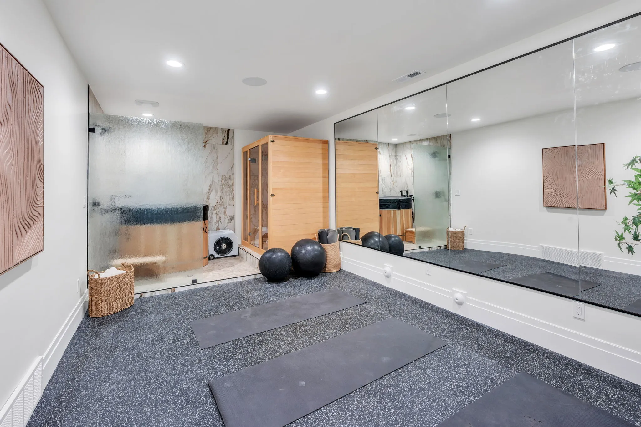 Dedicated fitness space featuring rubberized flooring, a full-wall mirror, and recessed lighting
