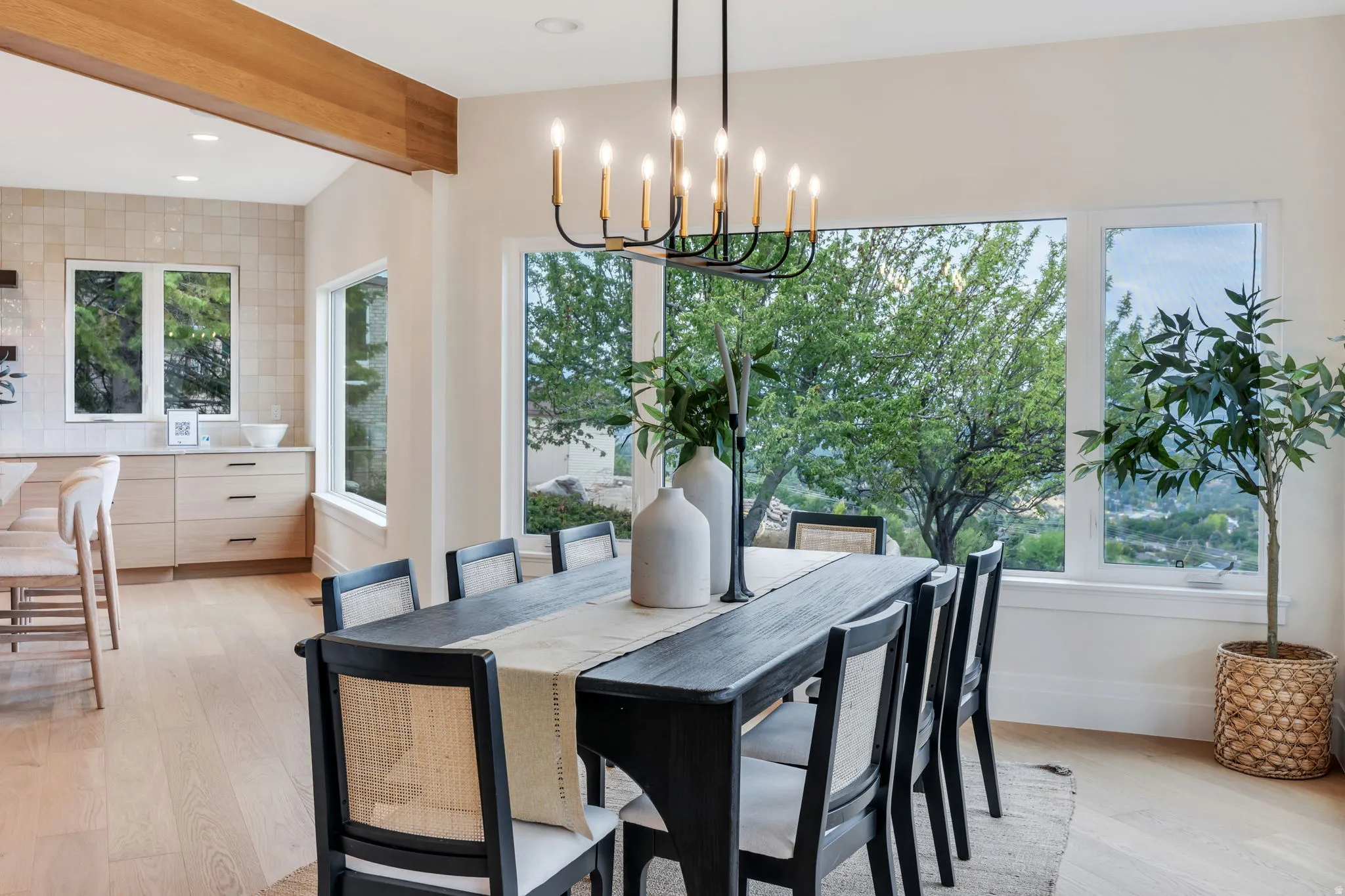 Dining area featuring a modern chandelier, extensive window-framing, light wood-finish flooring, and an exposed wood beam