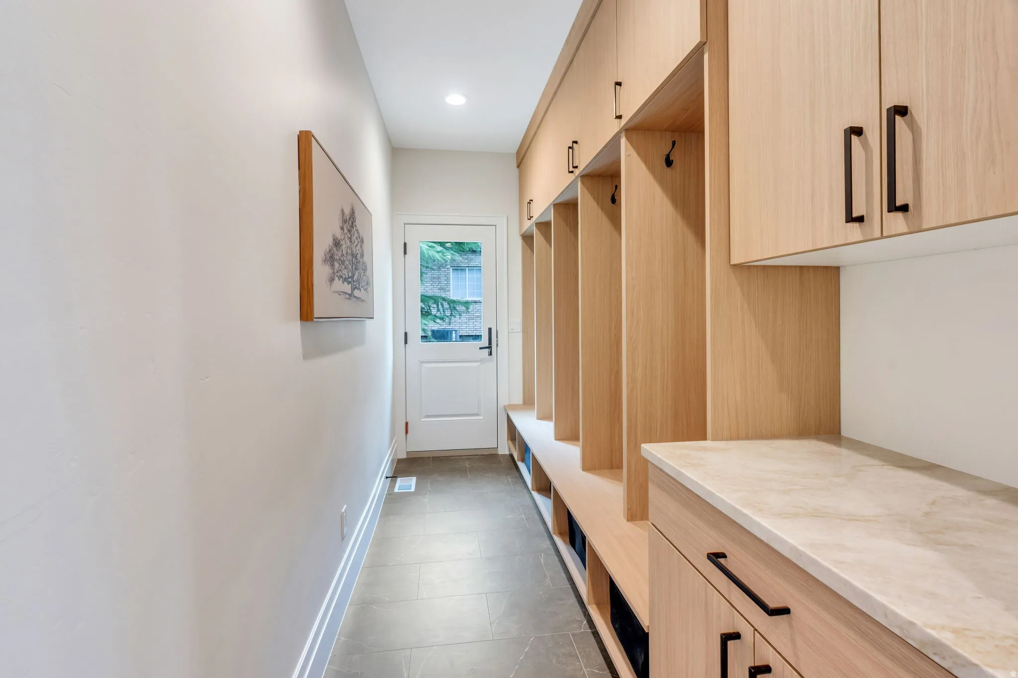 Entryway with built-in wood-finish cabinetry, integrated bench seating, and a stone-finish countertop