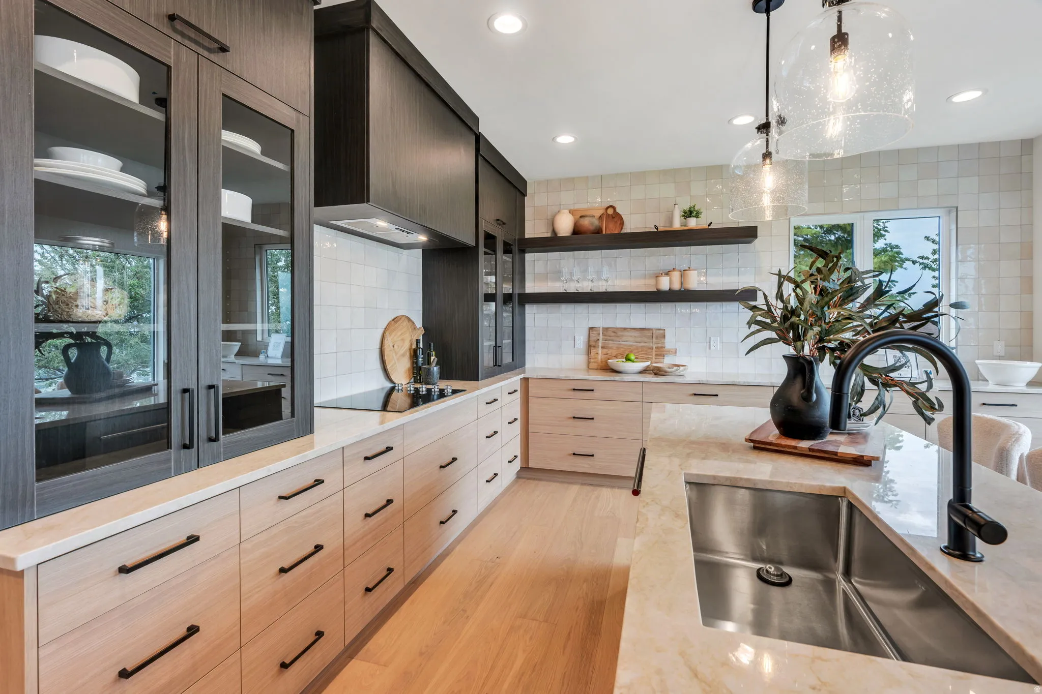 Modern kitchen featuring a large island with an undermount sink, a matte black faucet, and stone countertops