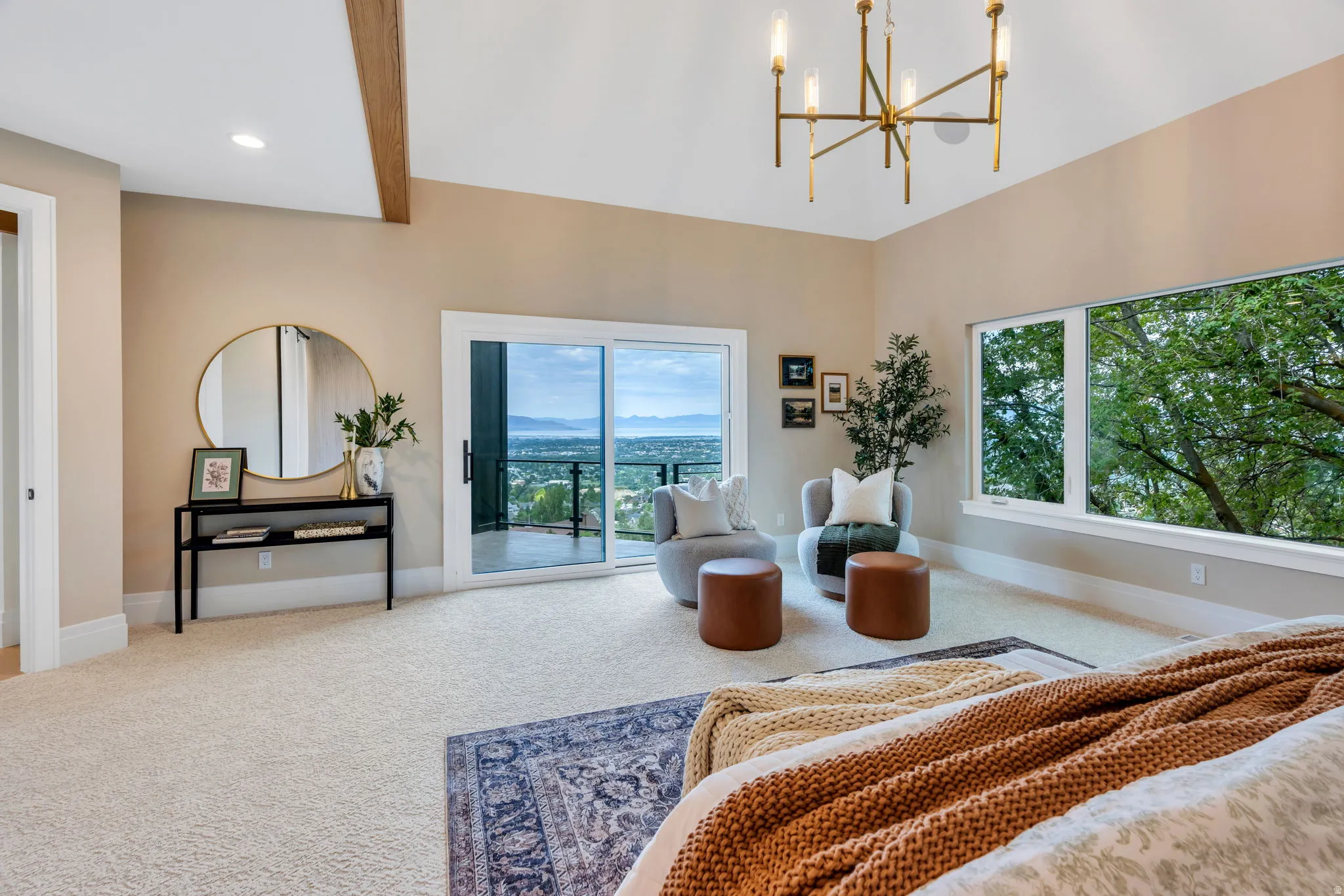 Spacious room featuring vaulted ceilings with exposed wood beams, a contemporary chandelier, and large windows providing expansive outdoor views