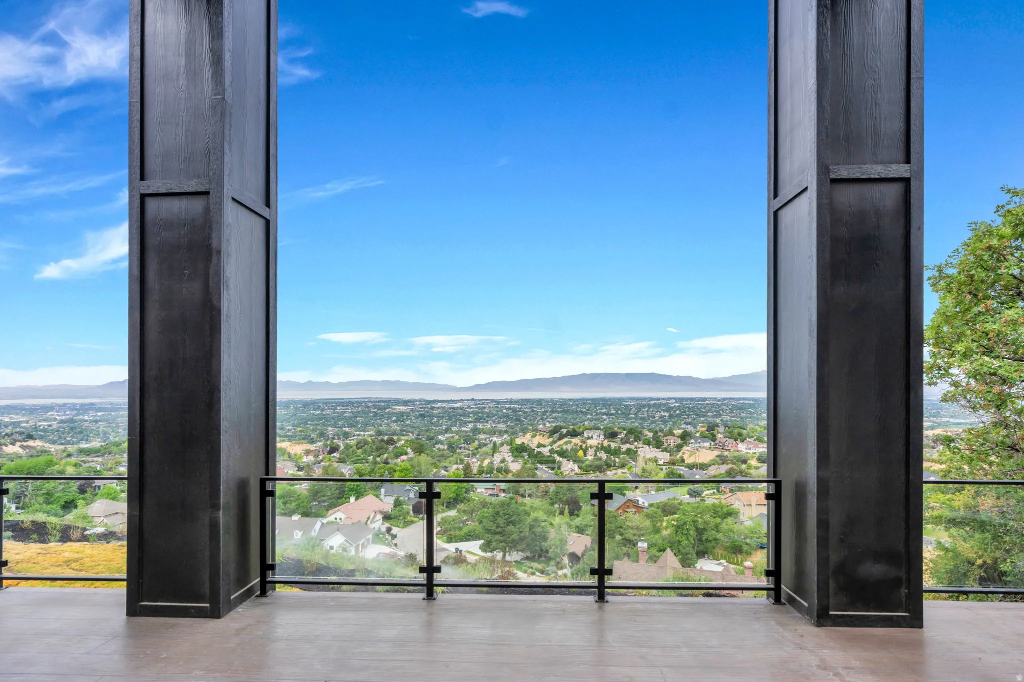 Exterior balcony with a glass railing, showcasing a broad metropolitan landscape with distant mountains