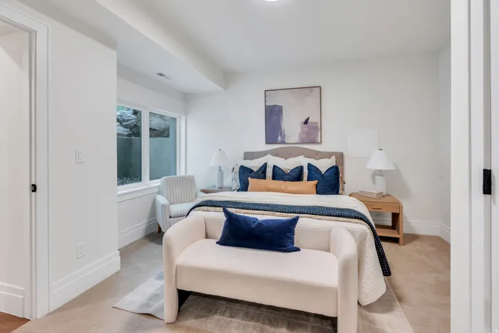 Bedroom with neutral carpeting, white walls, and a large egress window