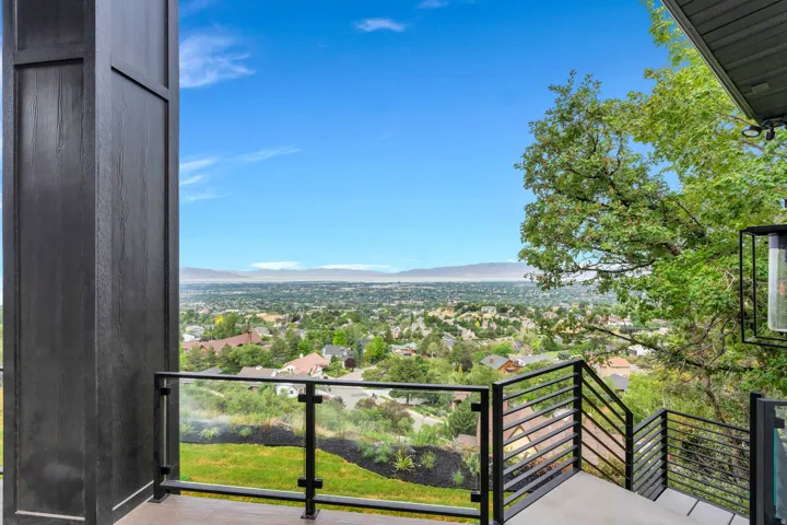Outdoor balcony featuring glass panel railings, black metal balusters, and concrete flooring
