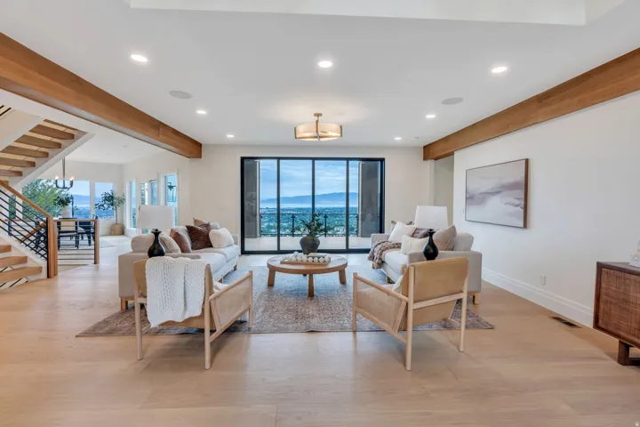 Spacious living area featuring light wood-finish flooring, a contemporary chandelier, and recessed lighting