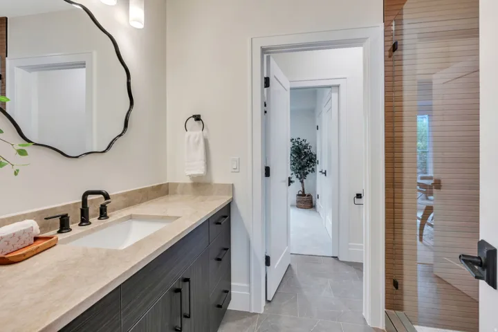 Bathroom vanity featuring a single undermount sink, a wide countertop, and dark wood-finish cabinetry with matte black hardware