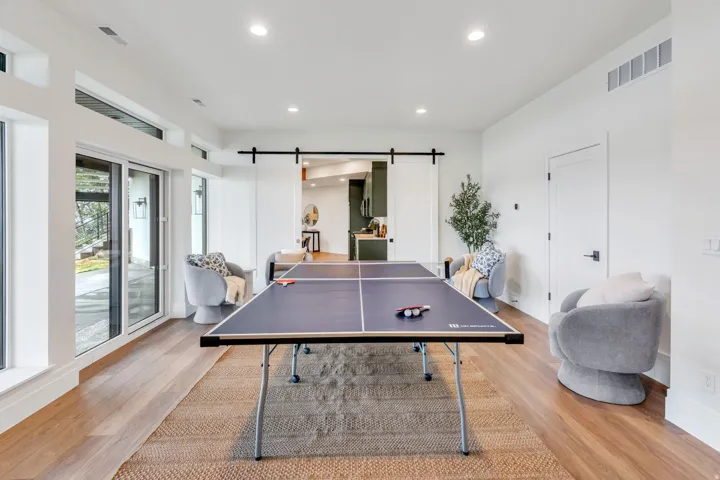 Spacious room with wood-finish flooring, a contemporary area rug, and recessed lighting