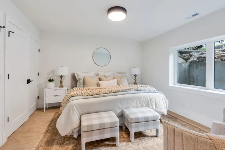 White paneled doors with black hardware, flush mount ceiling lighting, and a large egress window