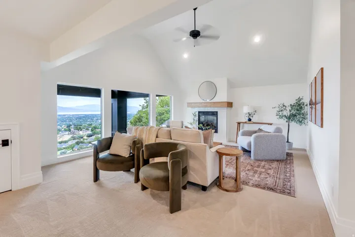 Living area featuring vaulted ceilings, a built-in fireplace with a wood mantel, recessed lighting, and large windows