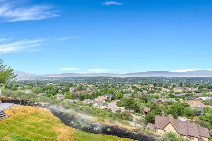 Expansive hillside property featuring a multi-level terraced lawn, a paved patio, and a sprinkler system