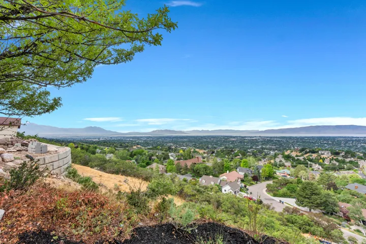 Expansive property featuring a curved retaining wall, sloped terrain, and a visible portion of a residential structure