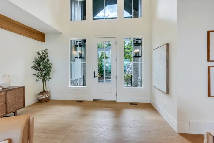 Bright entryway featuring a white paneled door with glass inserts, flanked by two side windows with black lantern-style sconces
