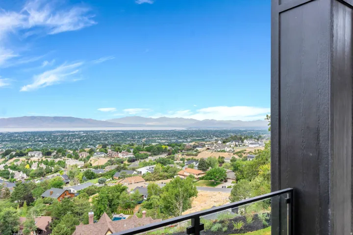 Expansive mountain and city scenery from a private balcony featuring a black metal and glass railing