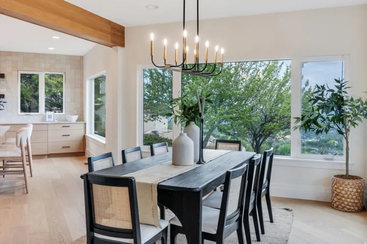 Dining area featuring a modern chandelier, extensive window-framing, light wood-finish flooring, and an exposed wood beam
