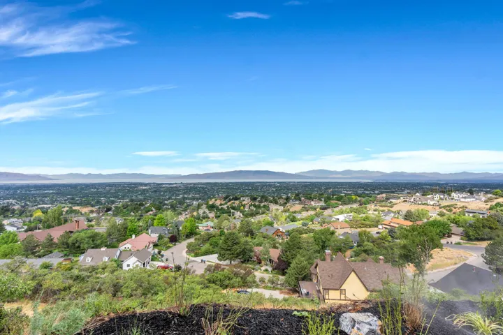 Expansive panoramic scenery featuring a residential area, distant mountains, and a clear blue sky