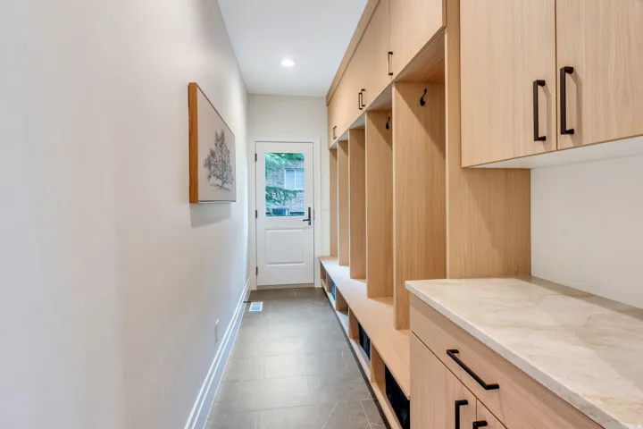 Entryway with built-in wood-finish cabinetry, integrated bench seating, and a stone-finish countertop