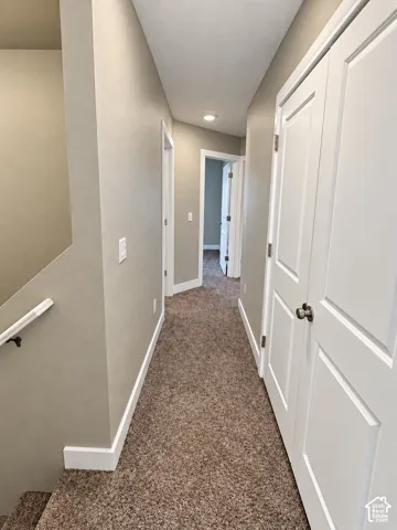 Hallway with neutral wall paint, recessed lighting, white trim, paneled doors, and carpeted flooring
