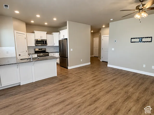Kitchen with white cabinetry, stainless steel appliances, and a central island with a sink